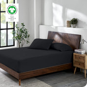 A bed made with a cotton jersey fitted sheet with 2 pillows near the headboard