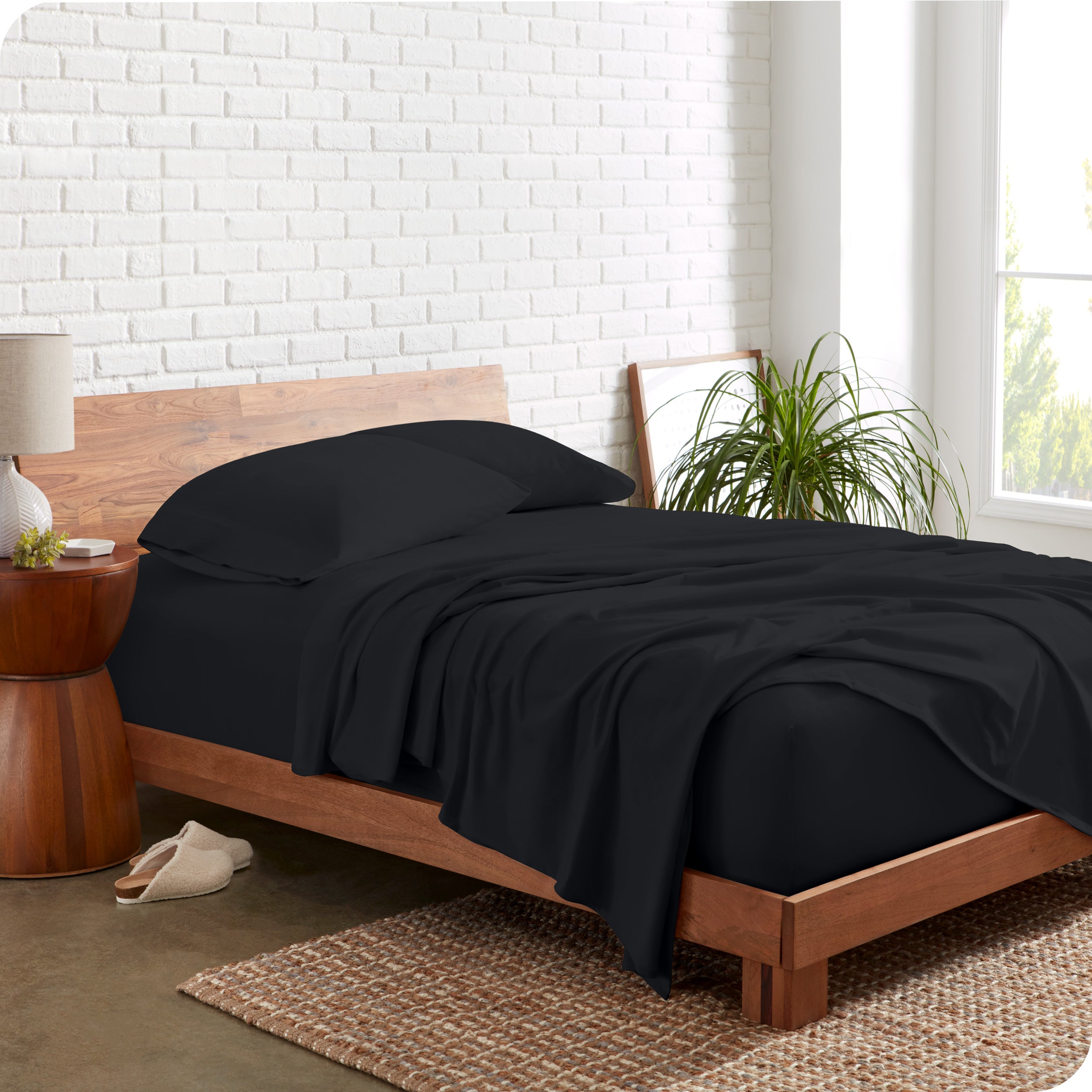Organic jersey sheets on a bed with a brick wall behind the headboard