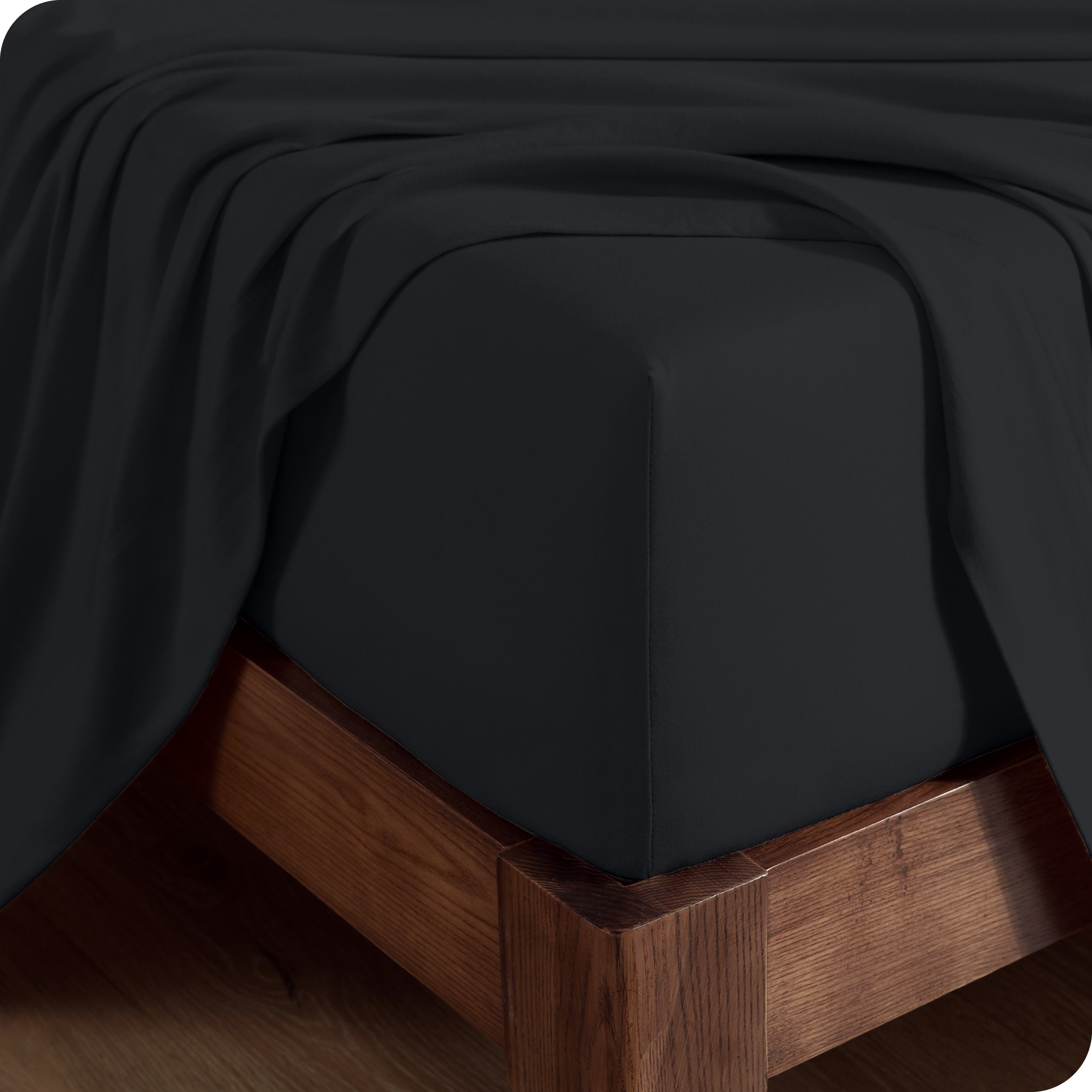 Close up of the corner of a mattress with a fitted sheet and flat sheet on it