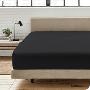 A percale fitted sheet on a bed with table next to it