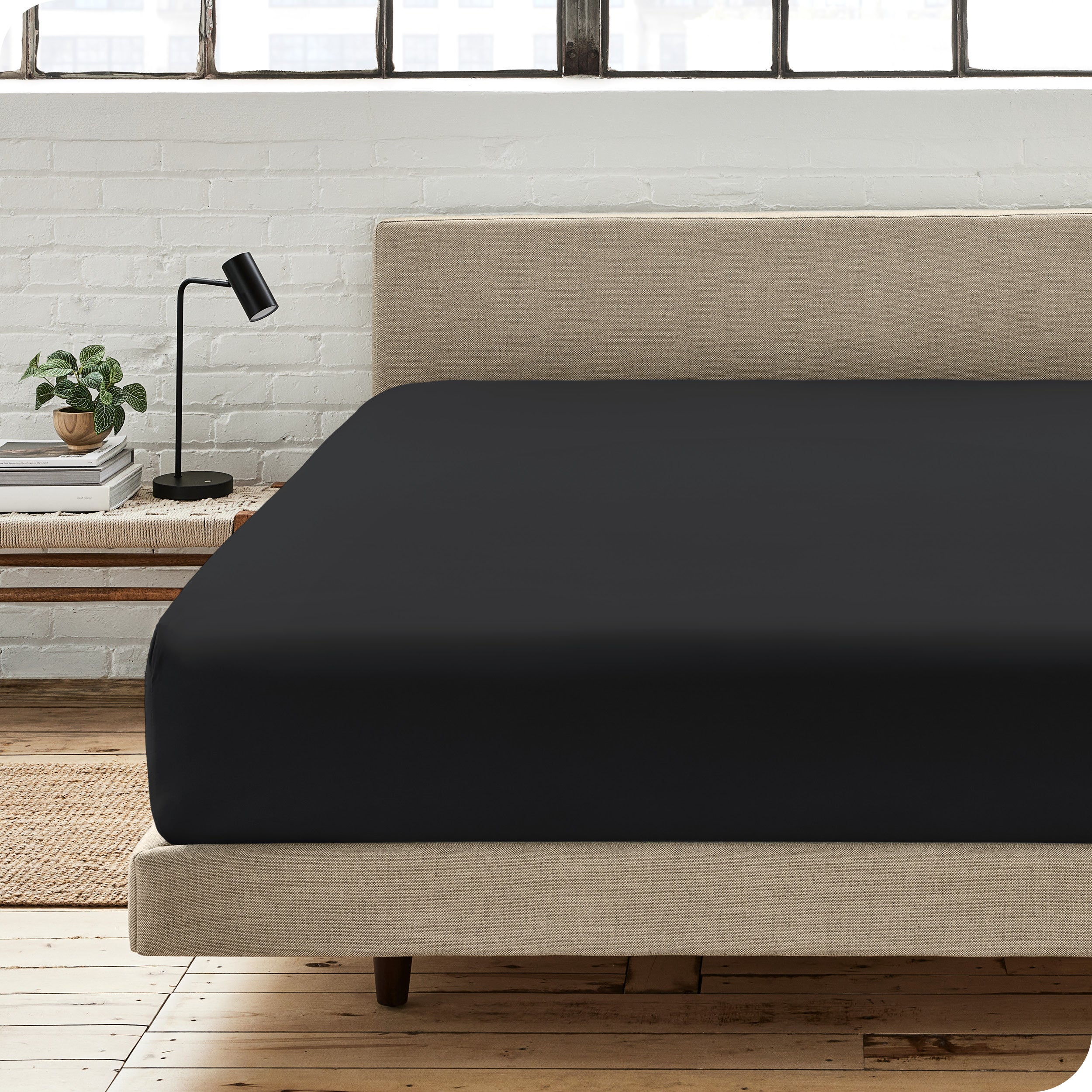 A percale fitted sheet on a bed with table next to it