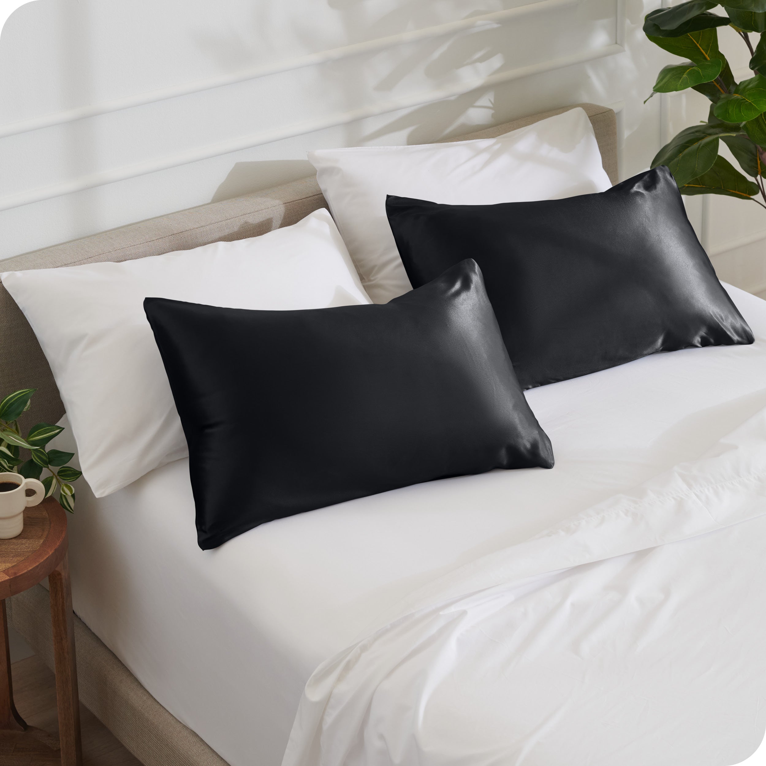 2 satin pillowcases on pillows leaning against other pillows on a bed