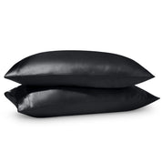 Two pillows on a white background with satin pillowcases on them.
