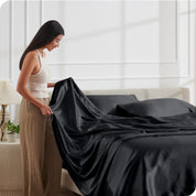 A woman making a bed with satin sheets