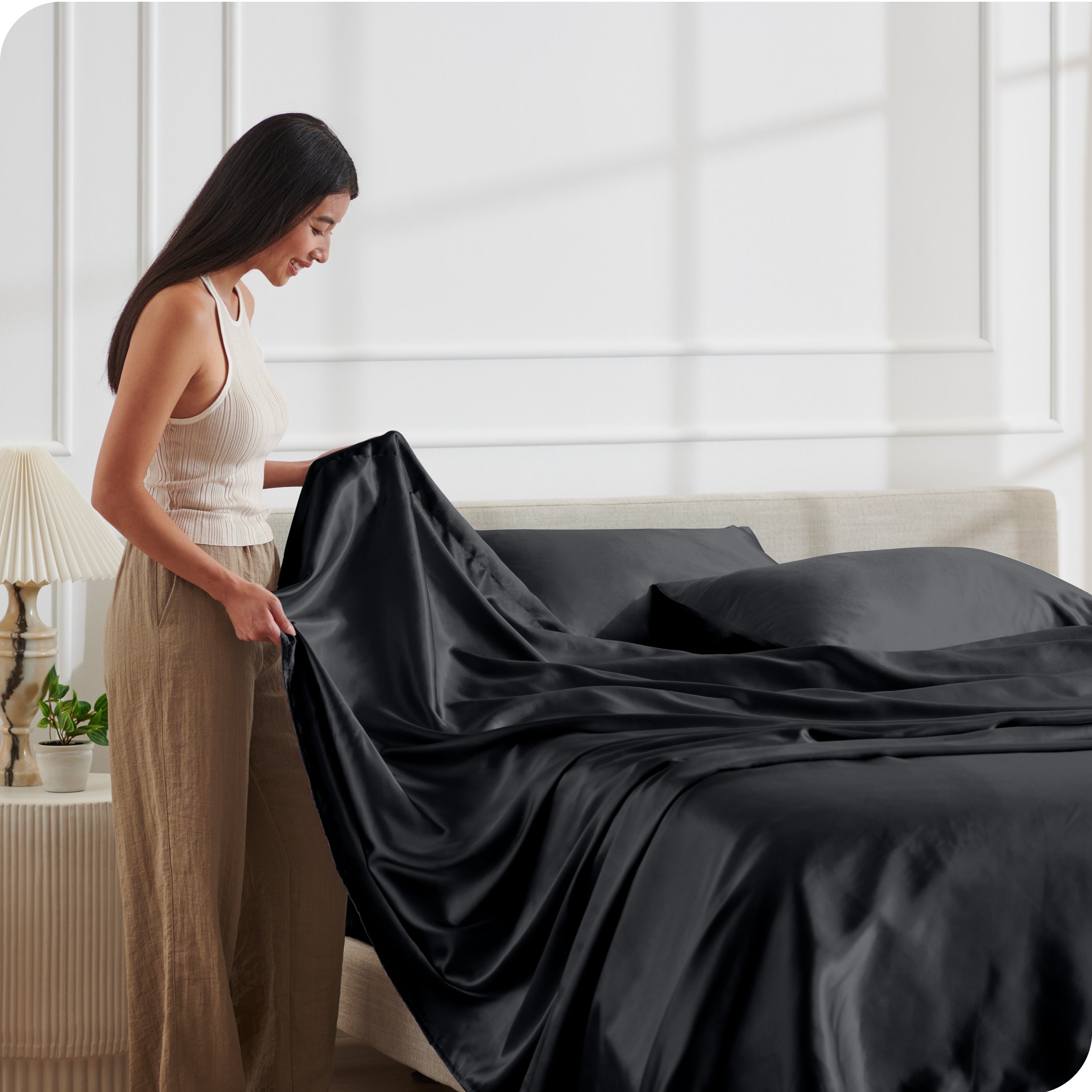 A woman making a bed with satin sheets