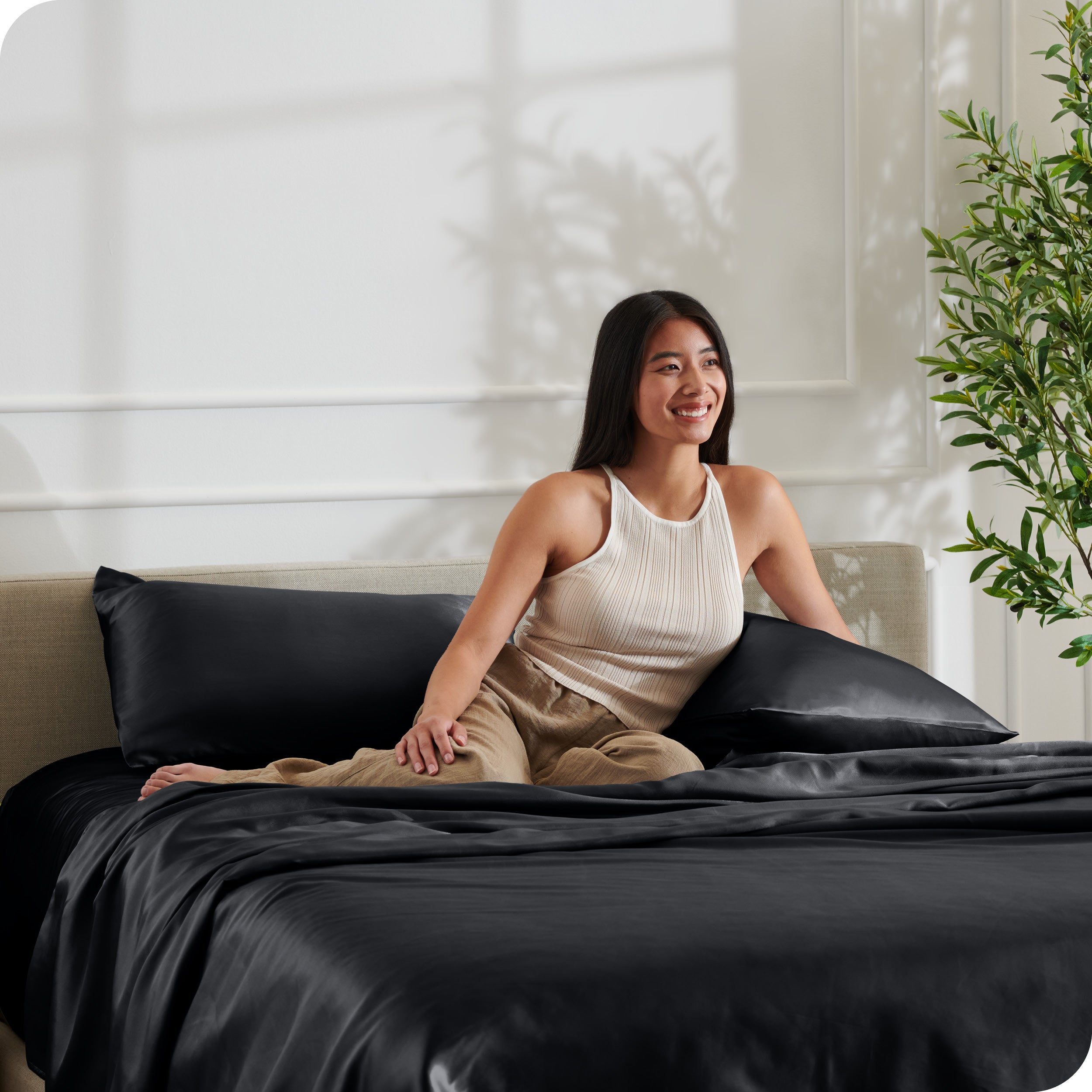 A woman sitting on a bed made with satin sheets