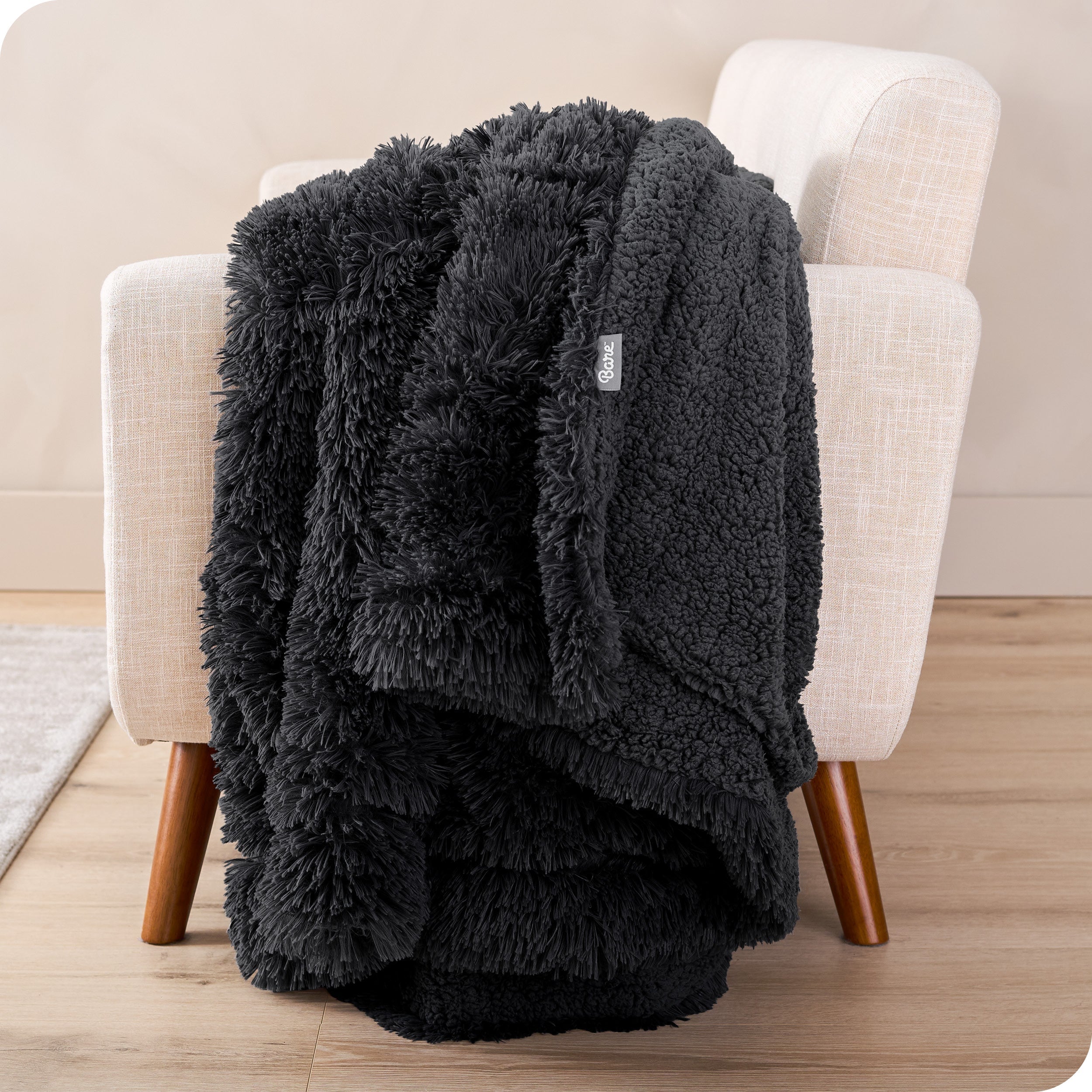 A shaggy faux fur blanket draped over the arm of a chair