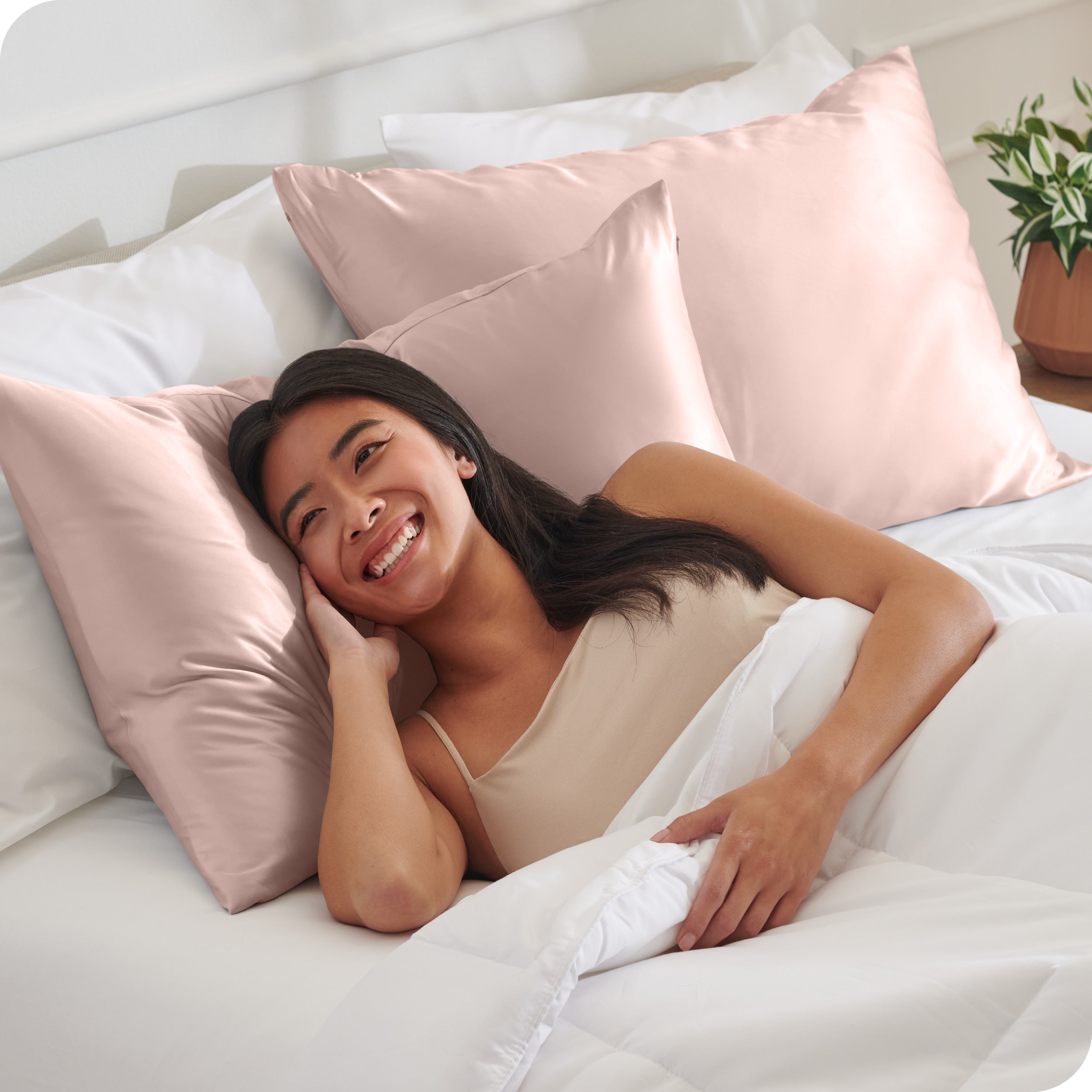 A woman in bed with her head resting on a silk pillowcase covered pillow