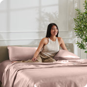 A woman sitting on a bed made with satin sheets