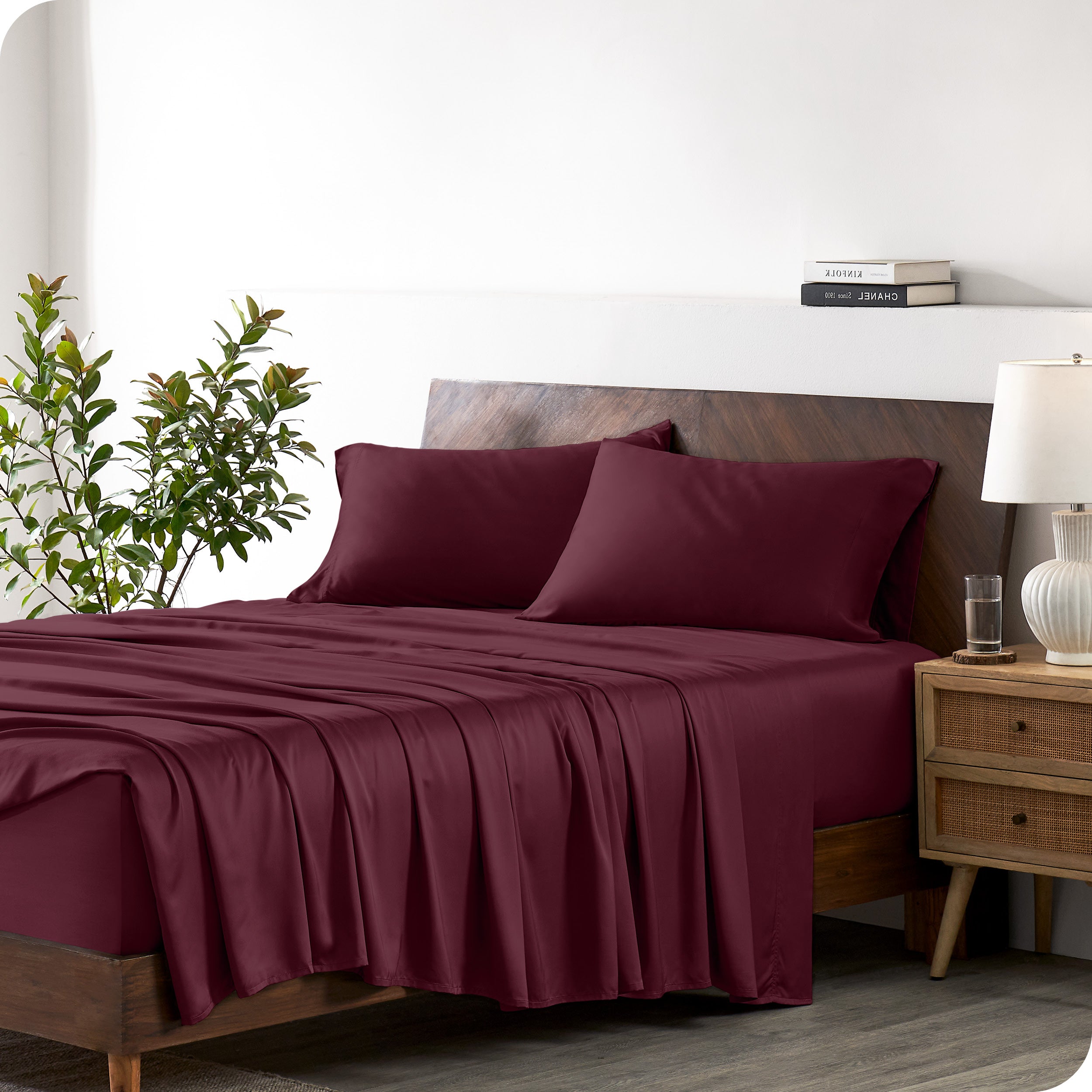 Modern bedroom with a bed against a white wall with a nightstand next to the bed. The bed has bamboo sheets draped over it.