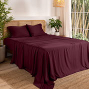 Bamboo sheets on a bed in a bedroom with plants and a window.
