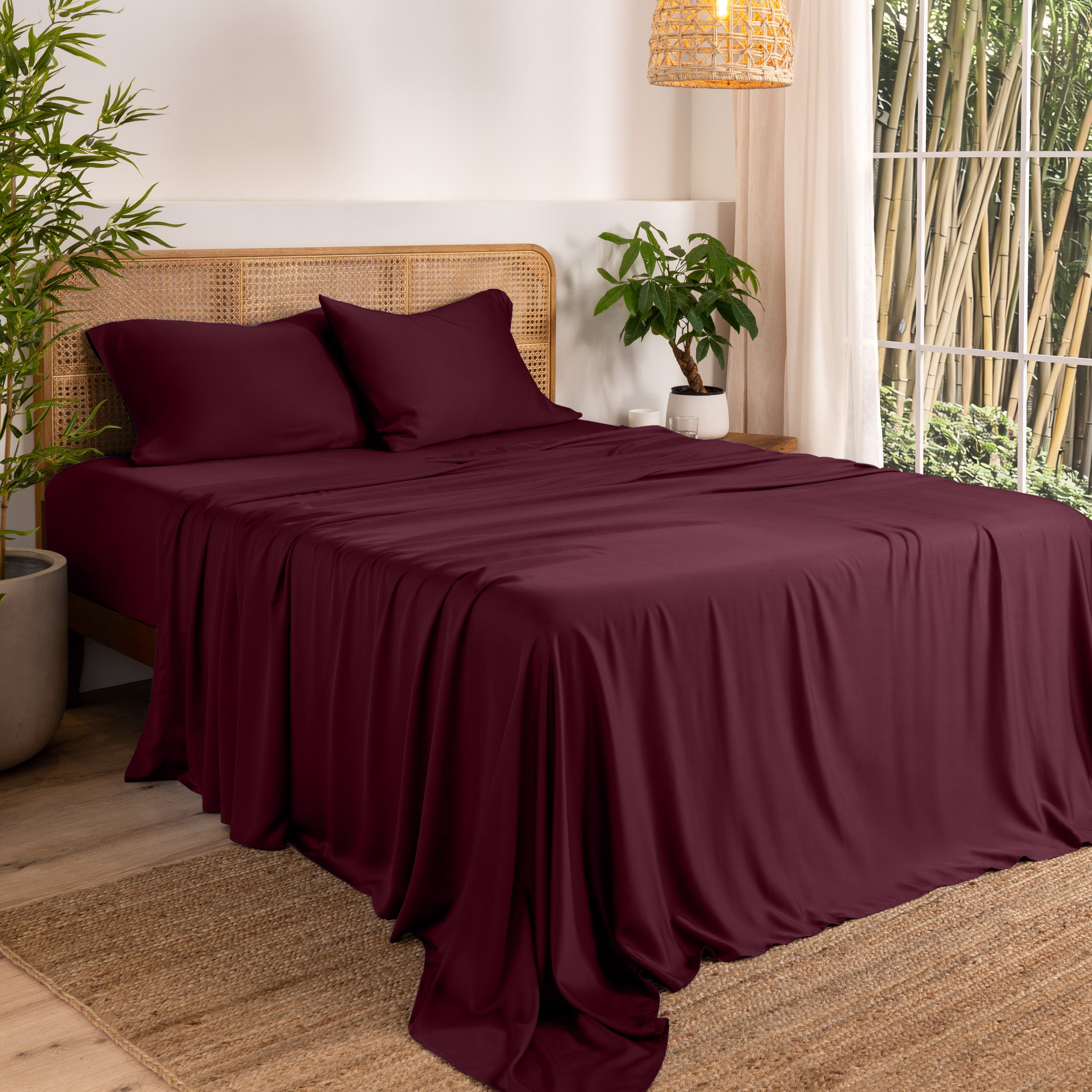Bamboo sheets on a bed in a bedroom with plants and a window.