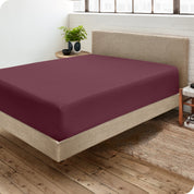 Corner view of a modern bed with a microfiber fitted sheet on the mattress. 