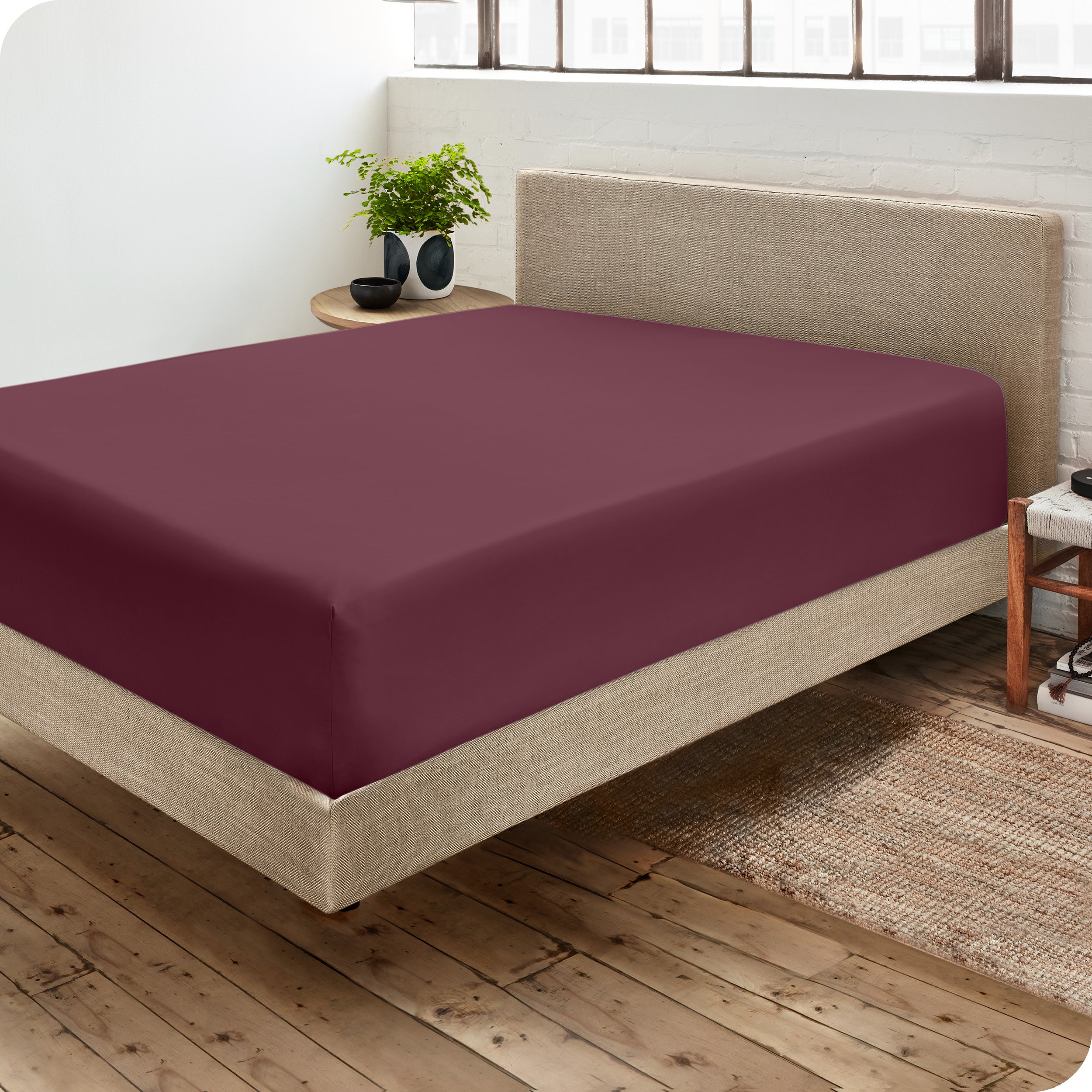 Corner view of a modern bed with a microfiber fitted sheet on the mattress. 