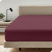 A bed with a microfiber fitted sheet on the mattress. 