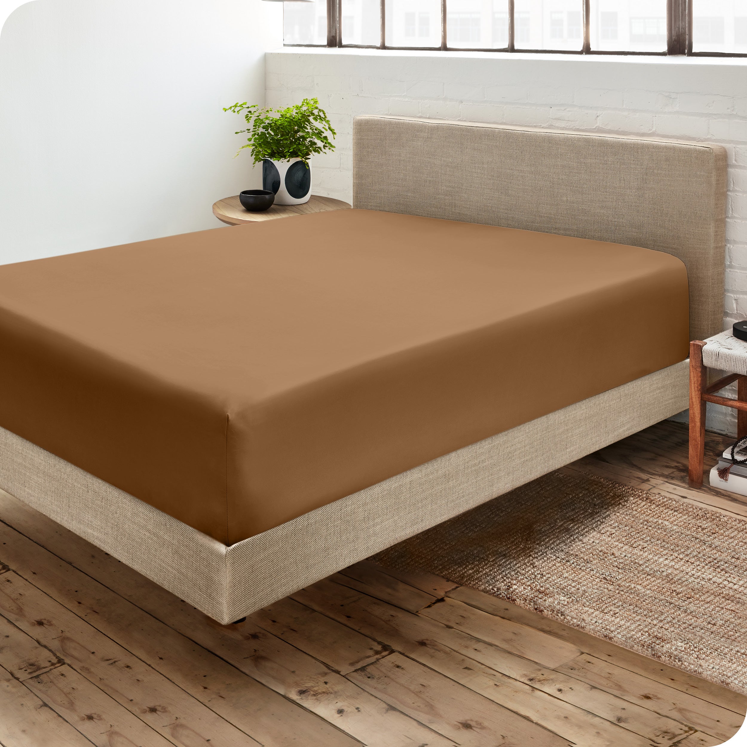 Corner view of a modern bed with a microfiber fitted sheet on the mattress. 