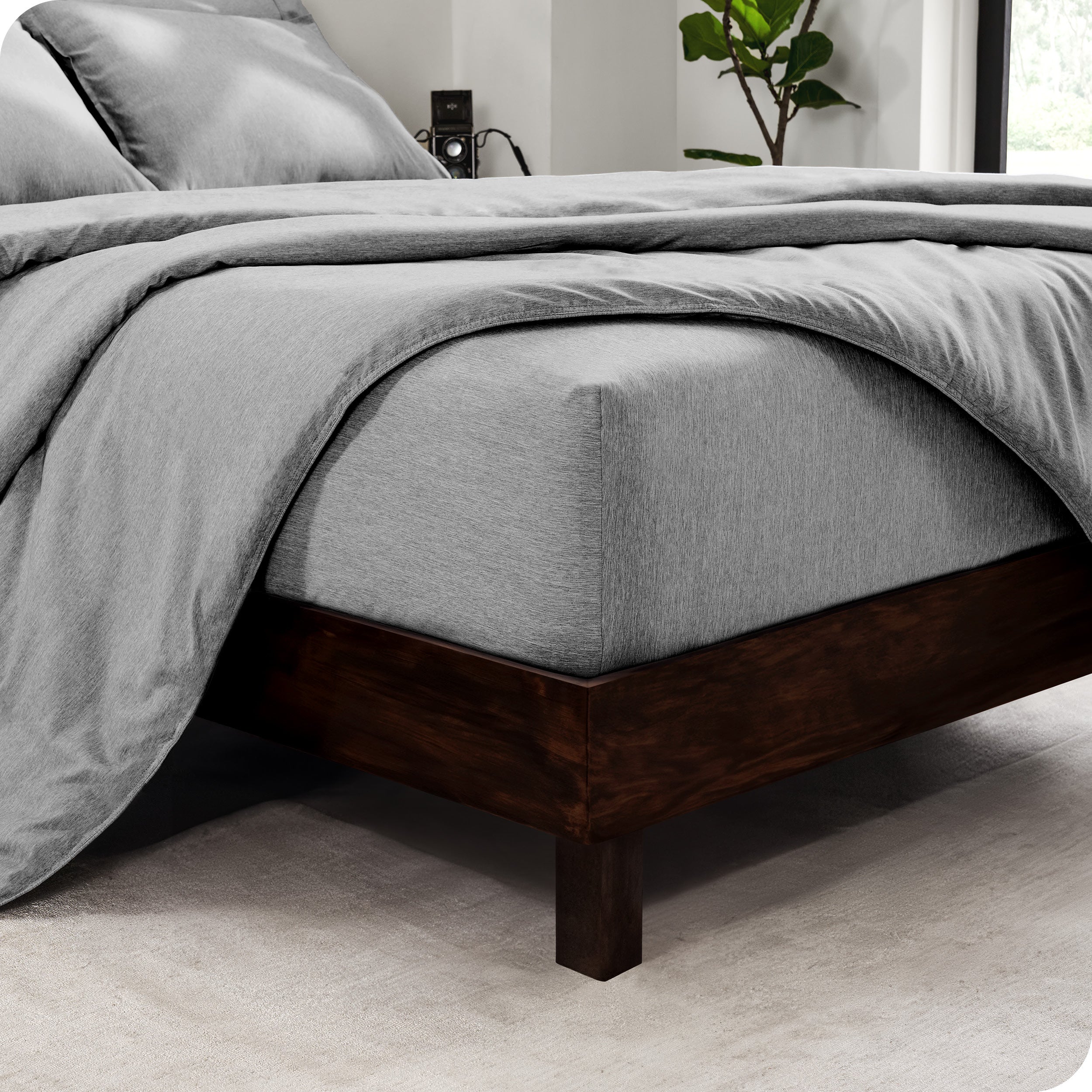 The corner of a mattress with a fitted sheet and comforter on it