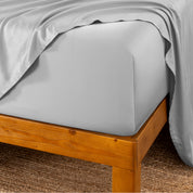 Bed sheets on a wooden bed frame with a brown carpet background