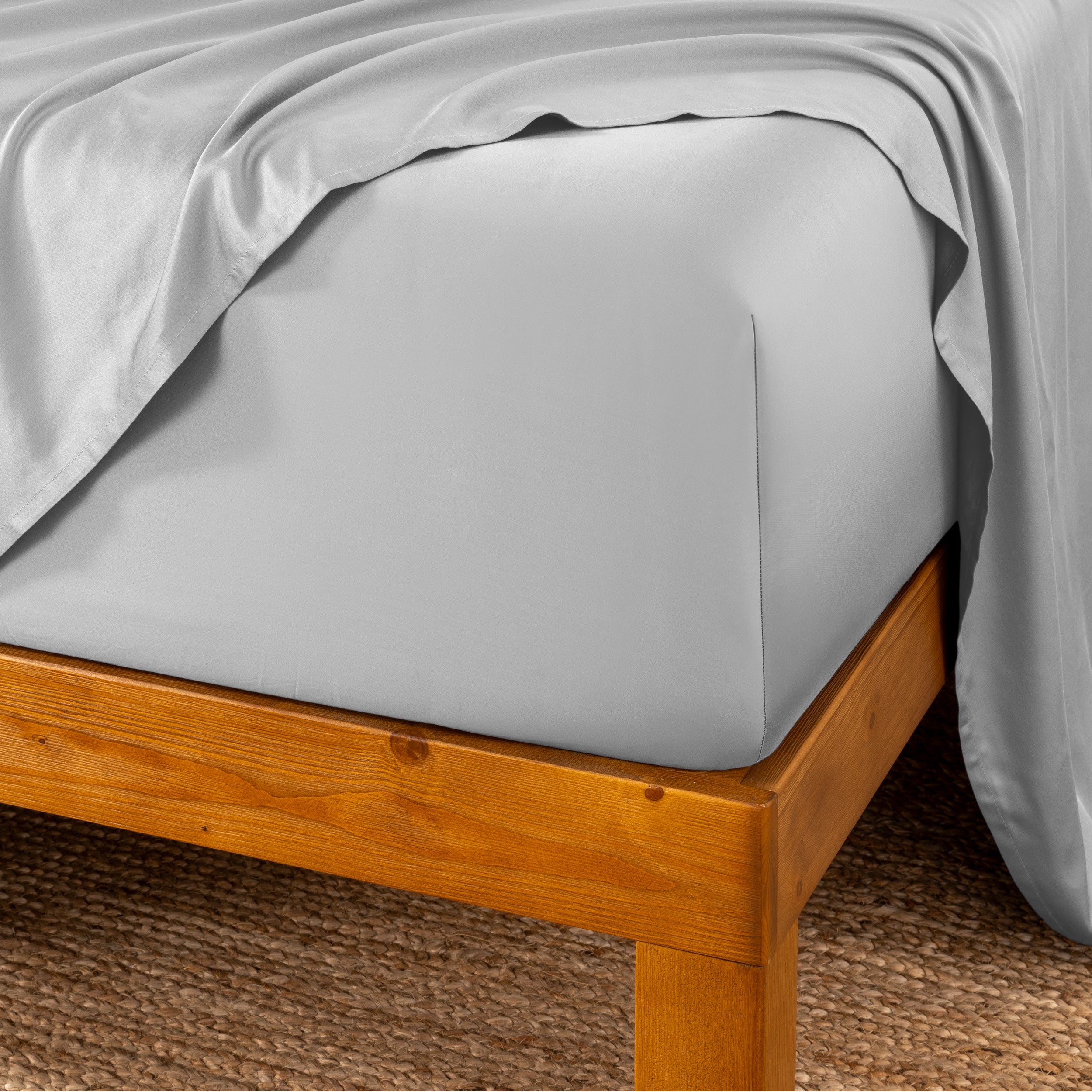 Bed sheets on a wooden bed frame with a brown carpet background