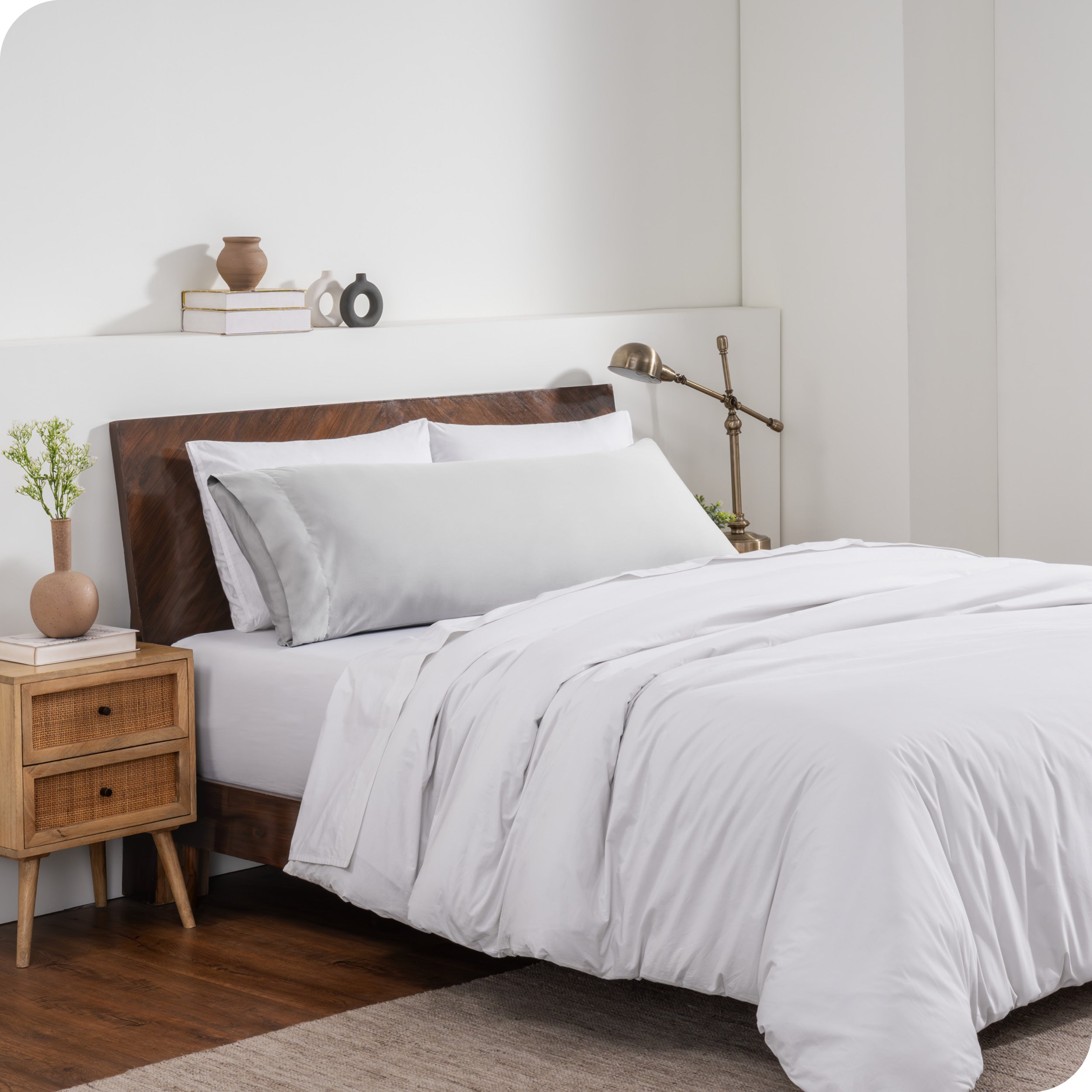 A body pillow cover on a pillow on a bed made with all white bedding