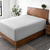 A wide corner view of a modern bed made with a microfiber fitted sheet on the mattress. 