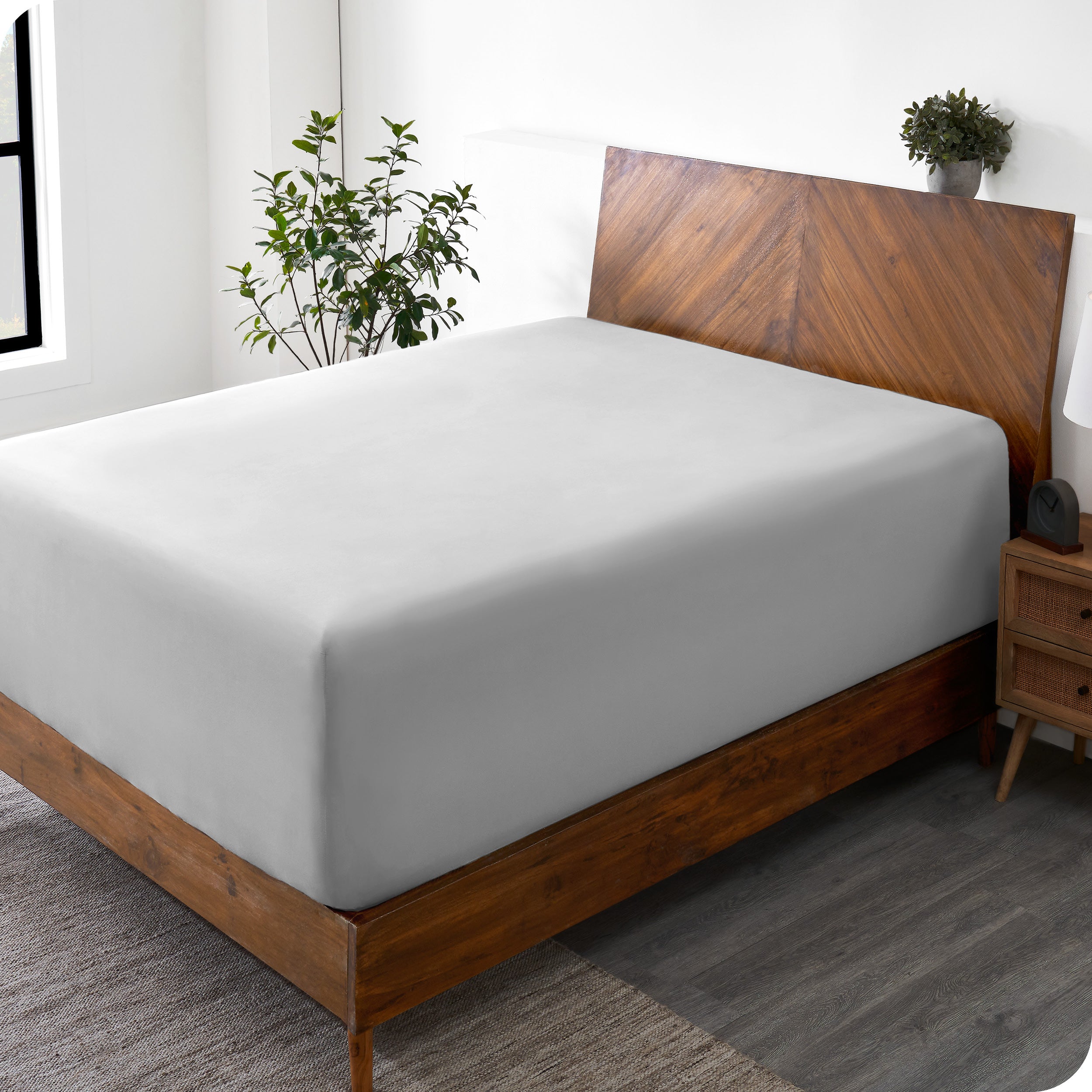 A wide corner view of a modern bed made with a microfiber fitted sheet on the mattress. 