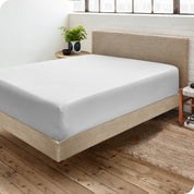Corner view of a modern bed with a microfiber fitted sheet on the mattress. 