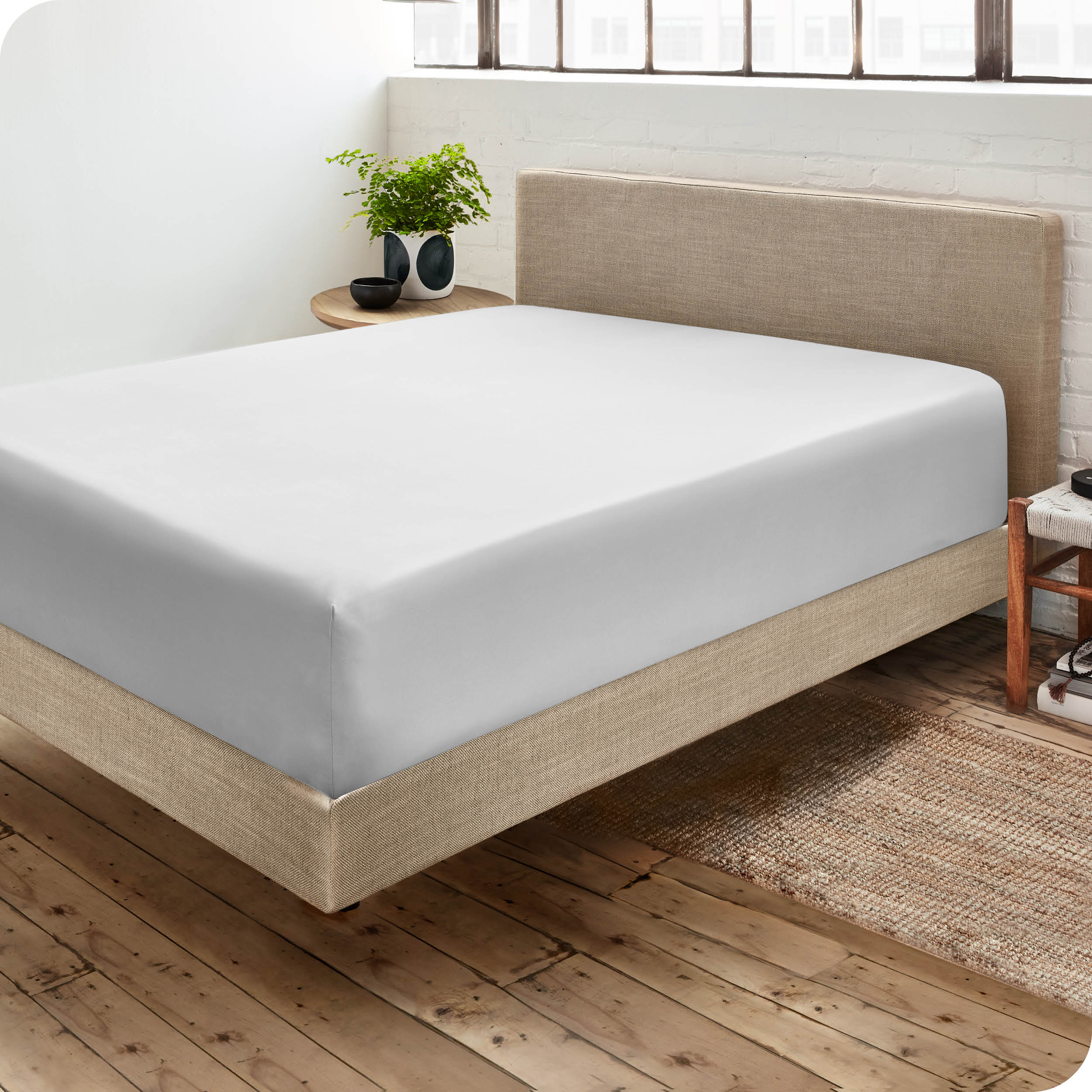 Corner view of a modern bed with a microfiber fitted sheet on the mattress. 