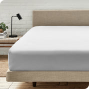 A bed with a microfiber fitted sheet on the mattress. 