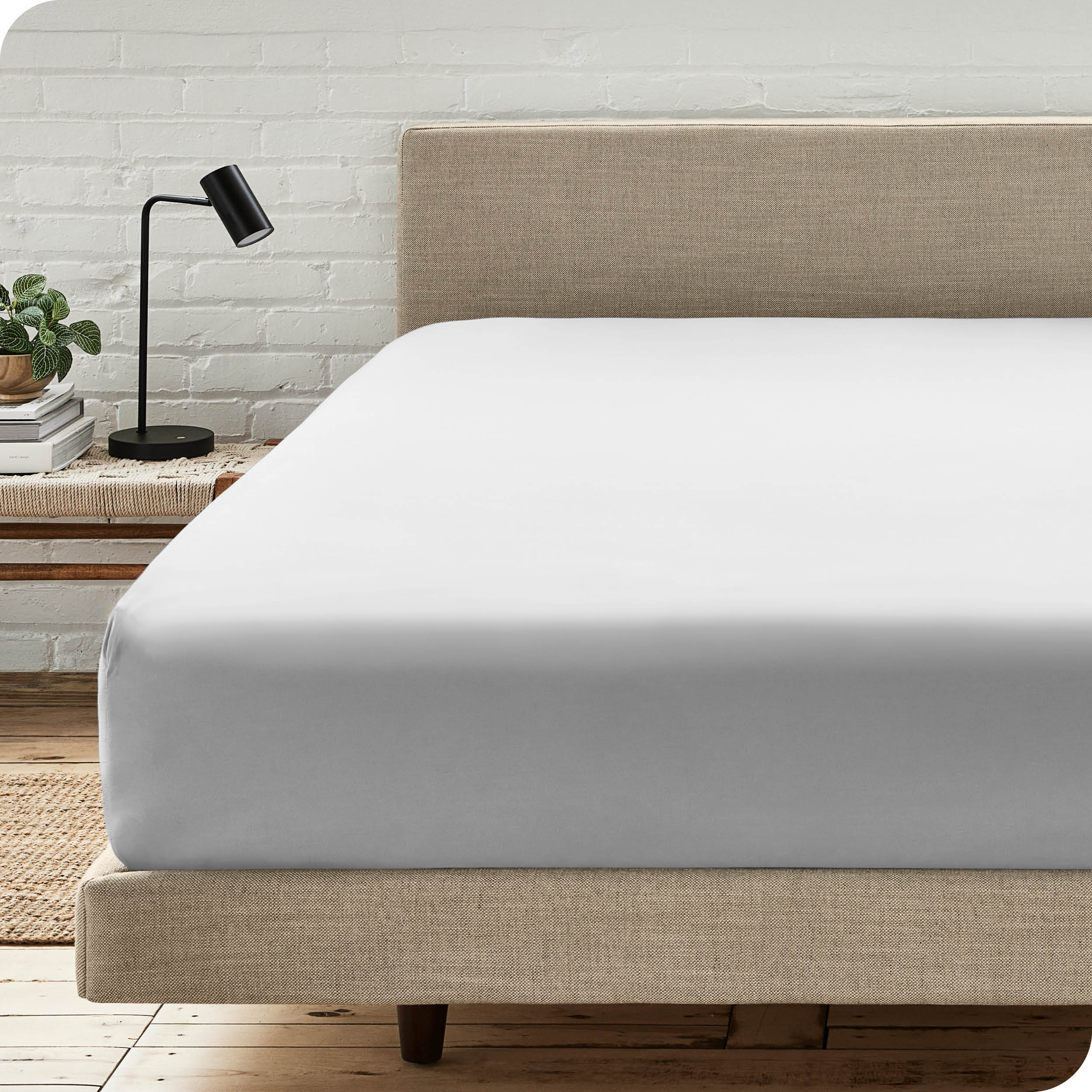 A bed with a microfiber fitted sheet on the mattress. 
