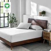 A bed made with a cotton jersey fitted sheet with 2 pillows near the headboard
