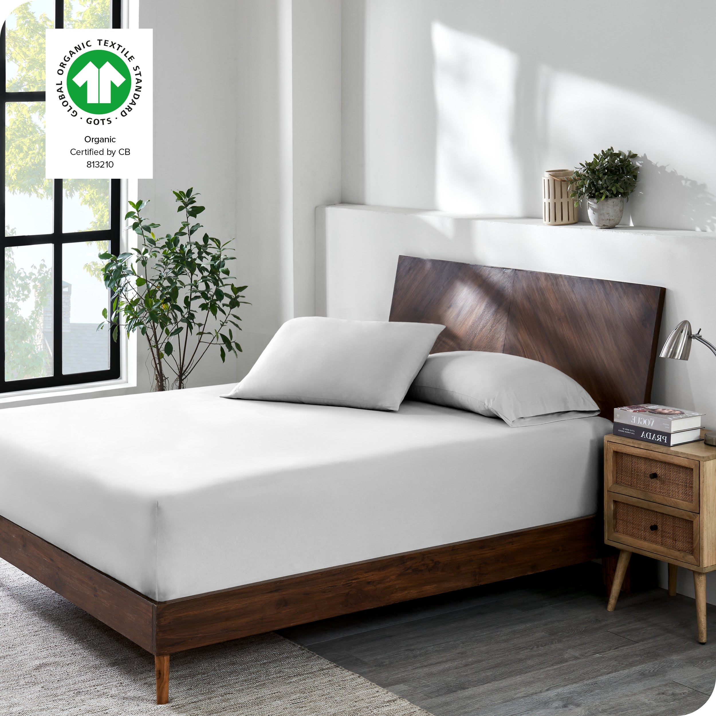 A bed made with a cotton jersey fitted sheet with 2 pillows near the headboard