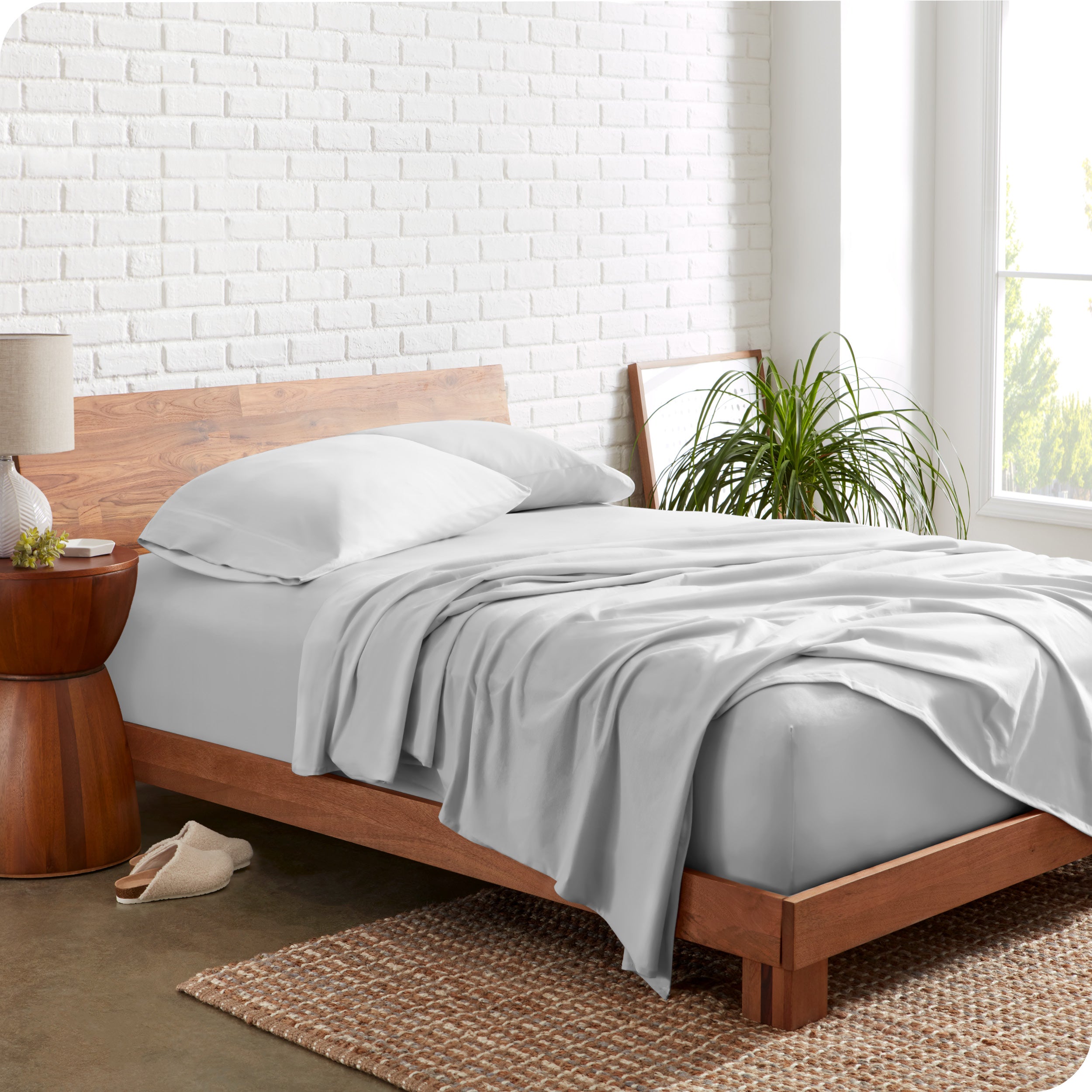 Organic jersey sheets on a bed with a brick wall behind the headboard