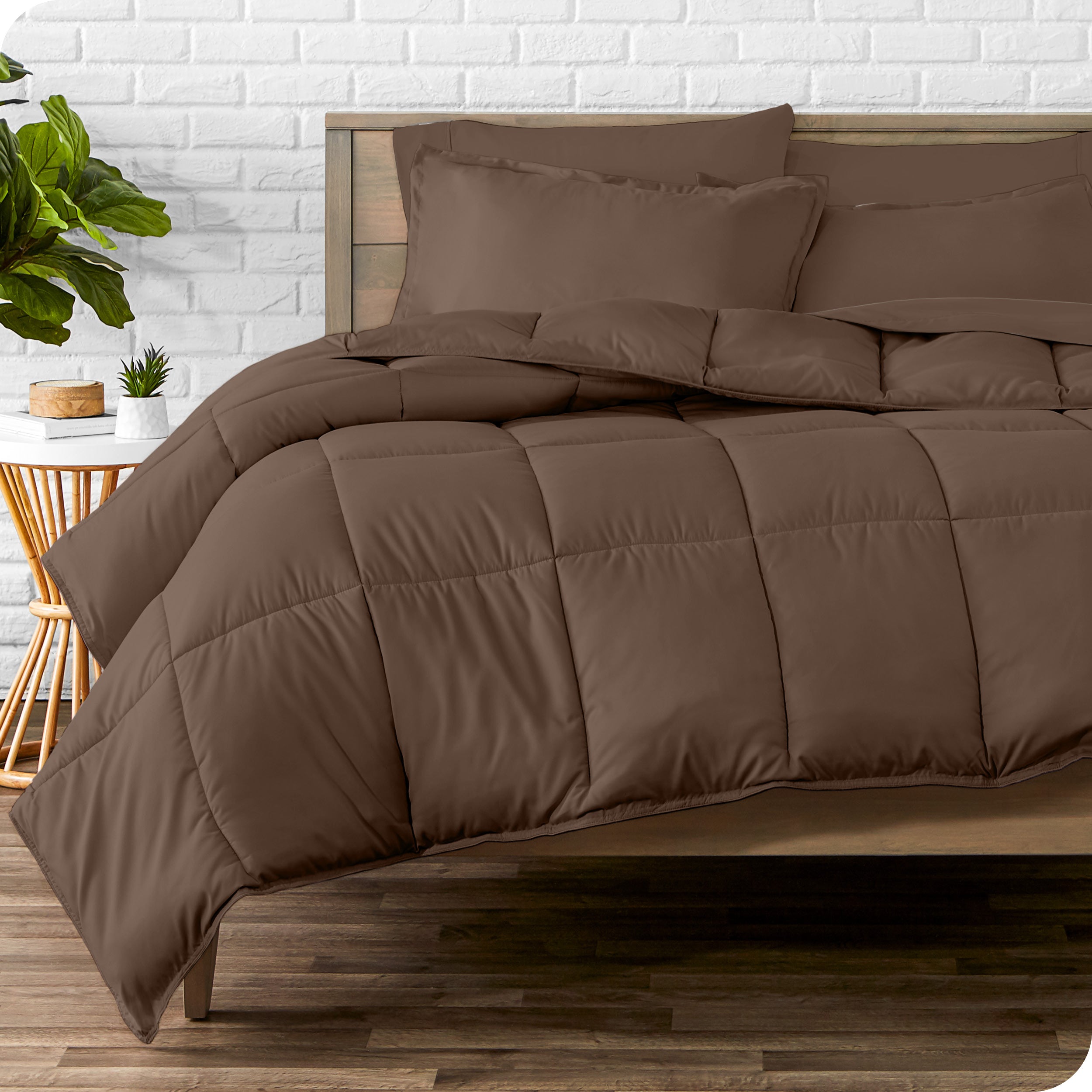 A wooden bed frame with sheets, pillow shams and a comforter on the bed