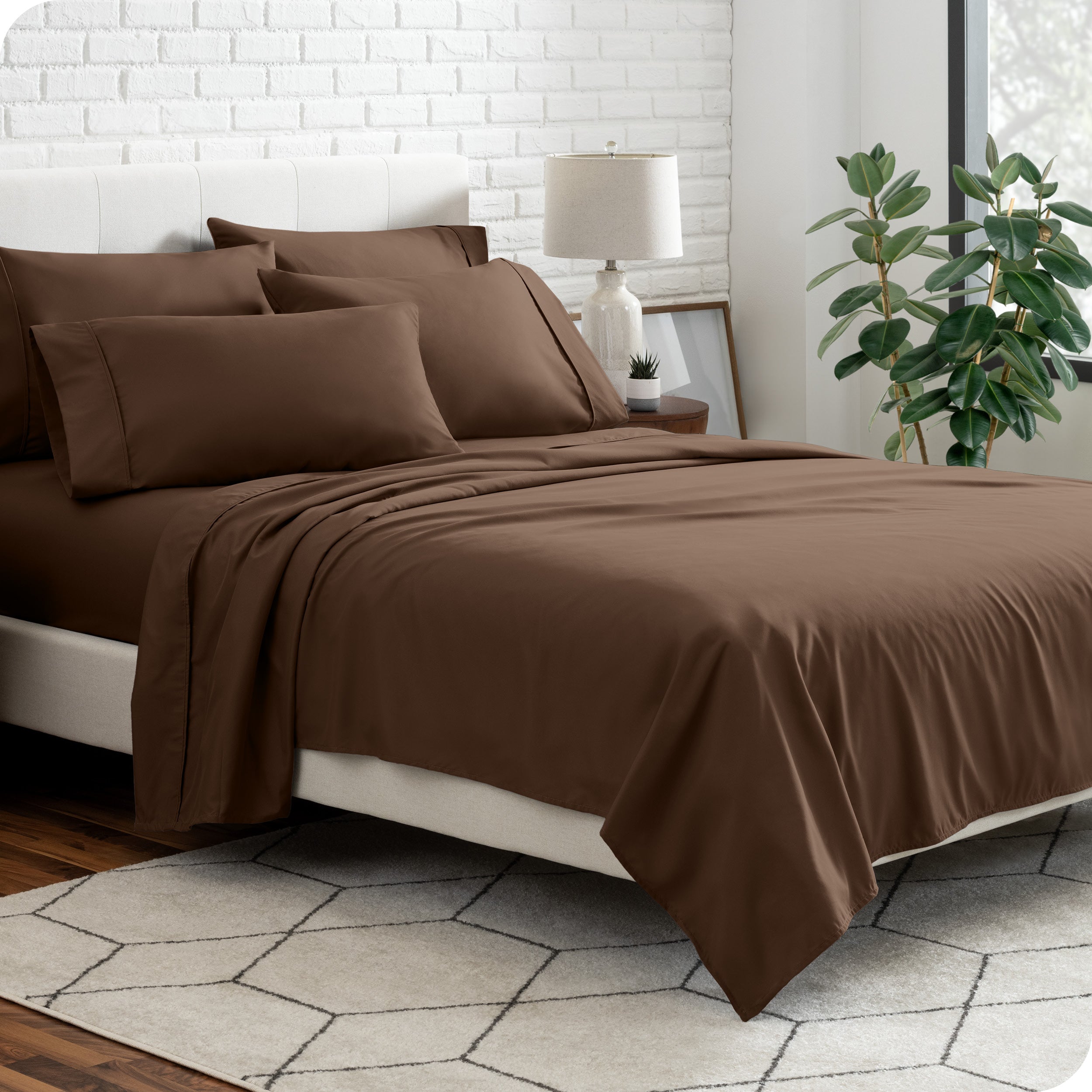 A bedroom setting with a bed made with the microfiber bed sheets and four pillows.