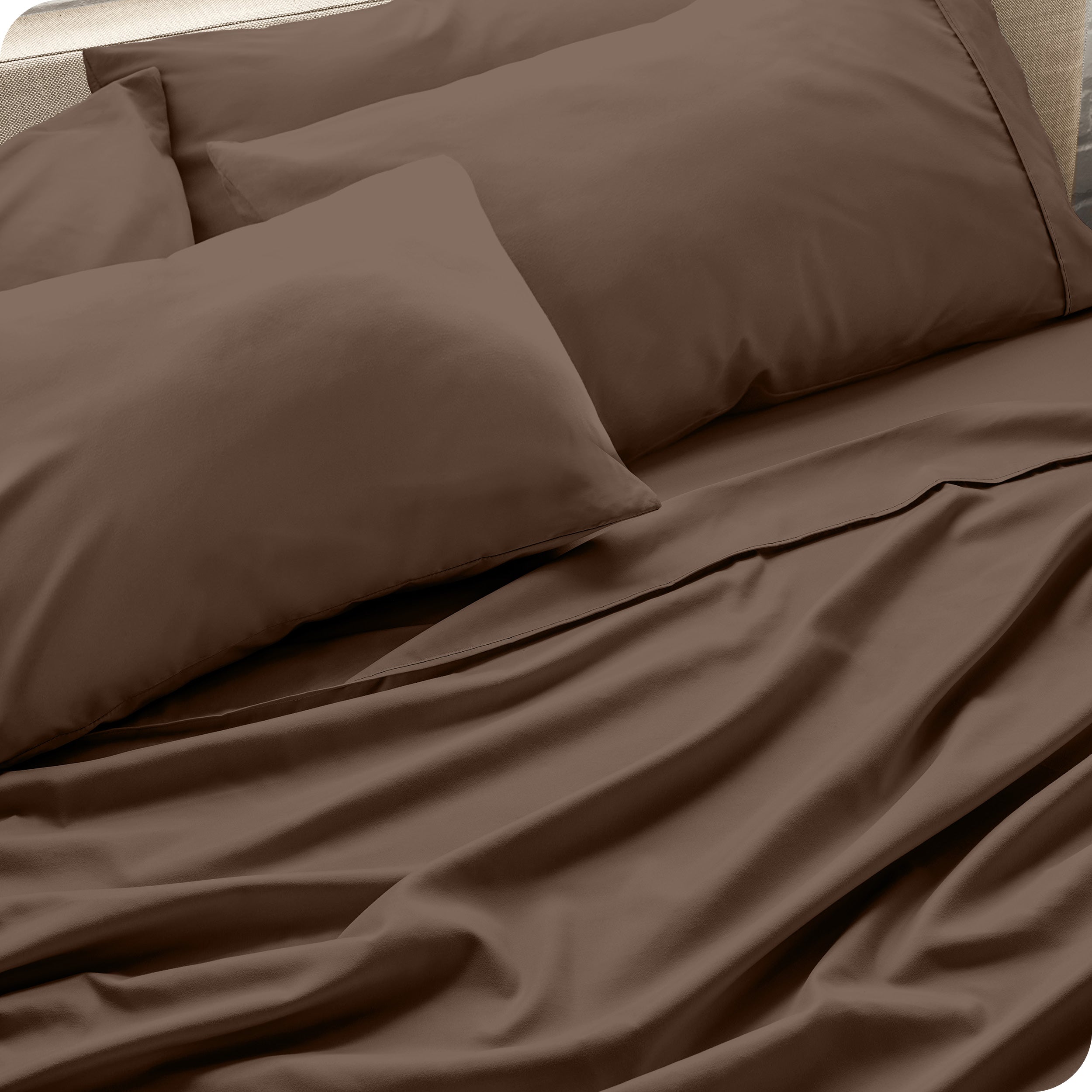 Close up of the microfiber bed sheets on a bed with four pillows.