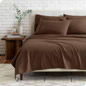 End view of a modern bed with the microfiber sheets on the bed with four pillows.