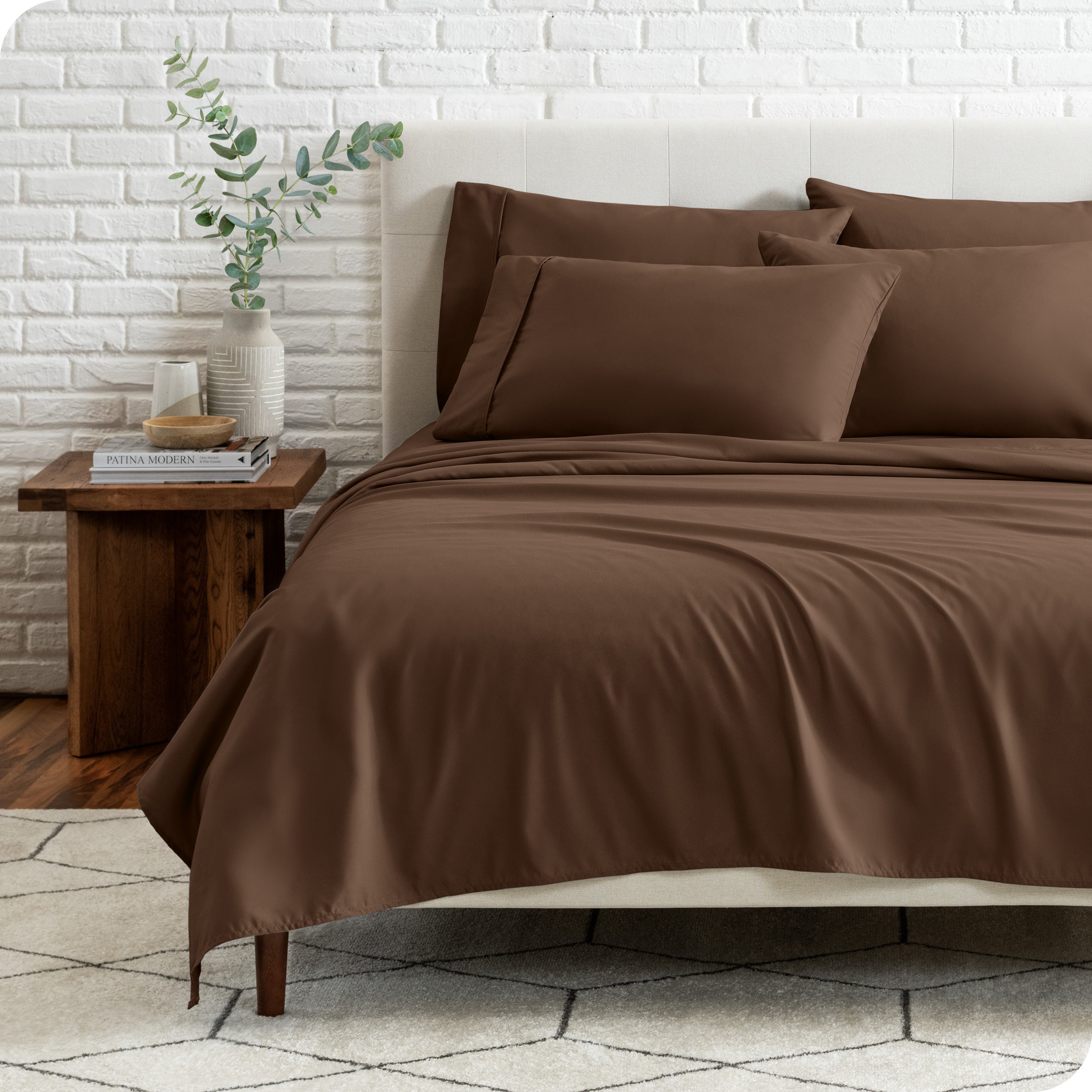 End view of a modern bed with the microfiber sheets on the bed with four pillows.
