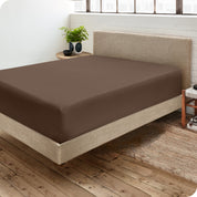 Corner view of a modern bed with a microfiber fitted sheet on the mattress. 