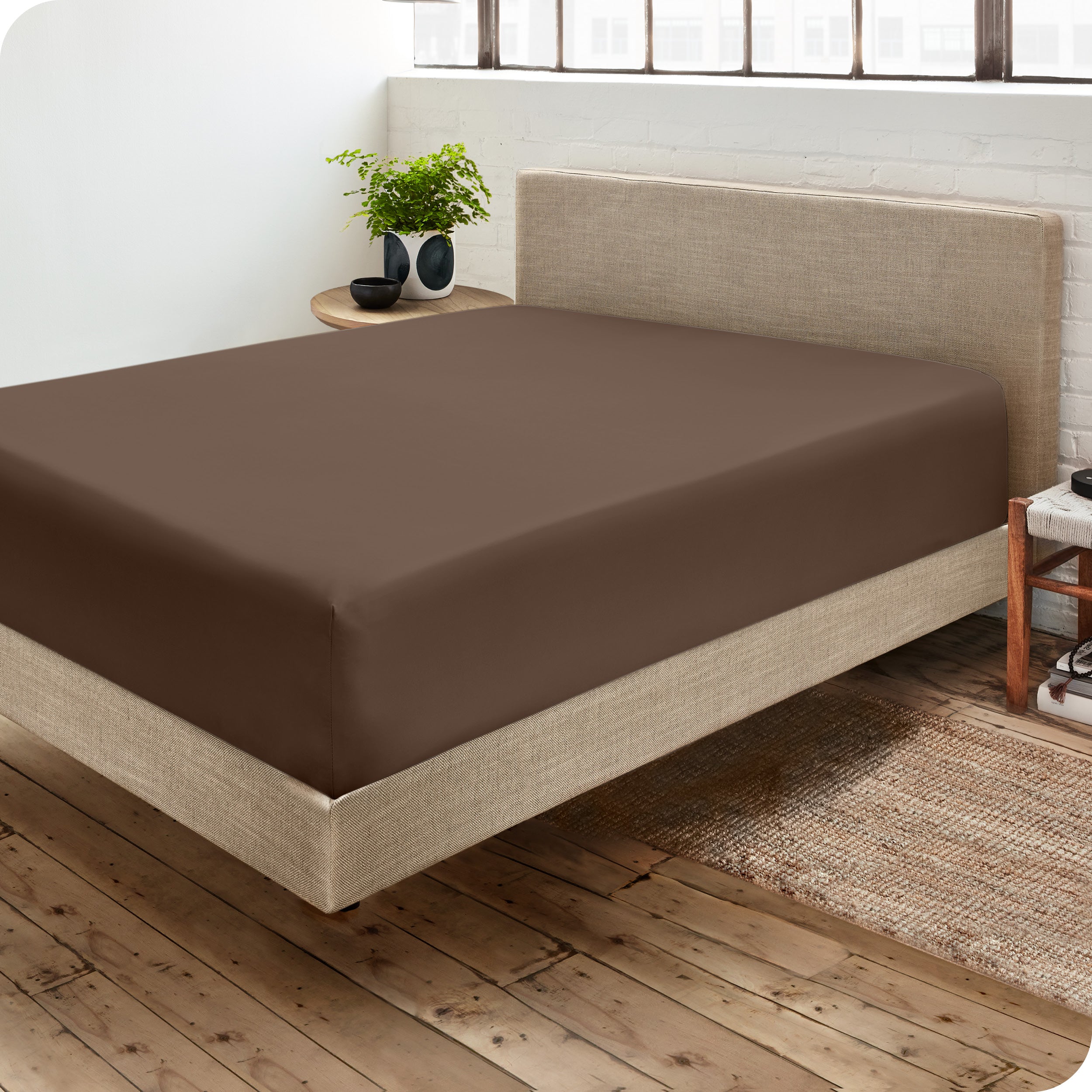 Corner view of a modern bed with a microfiber fitted sheet on the mattress. 