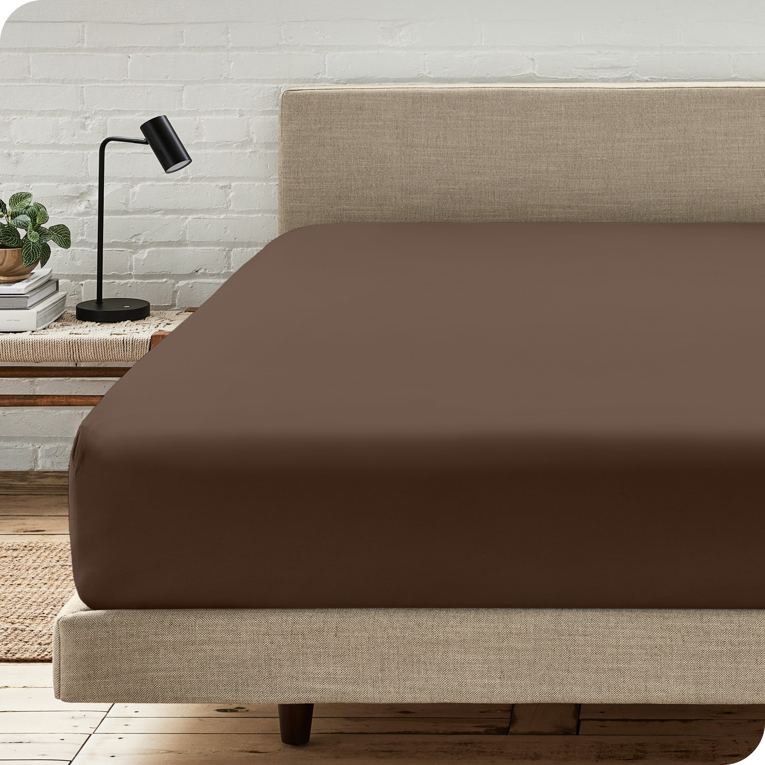 A bed with a microfiber fitted sheet on the mattress. 