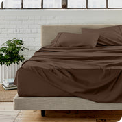 Microfiber sheets on a bed with a brick wall behind it