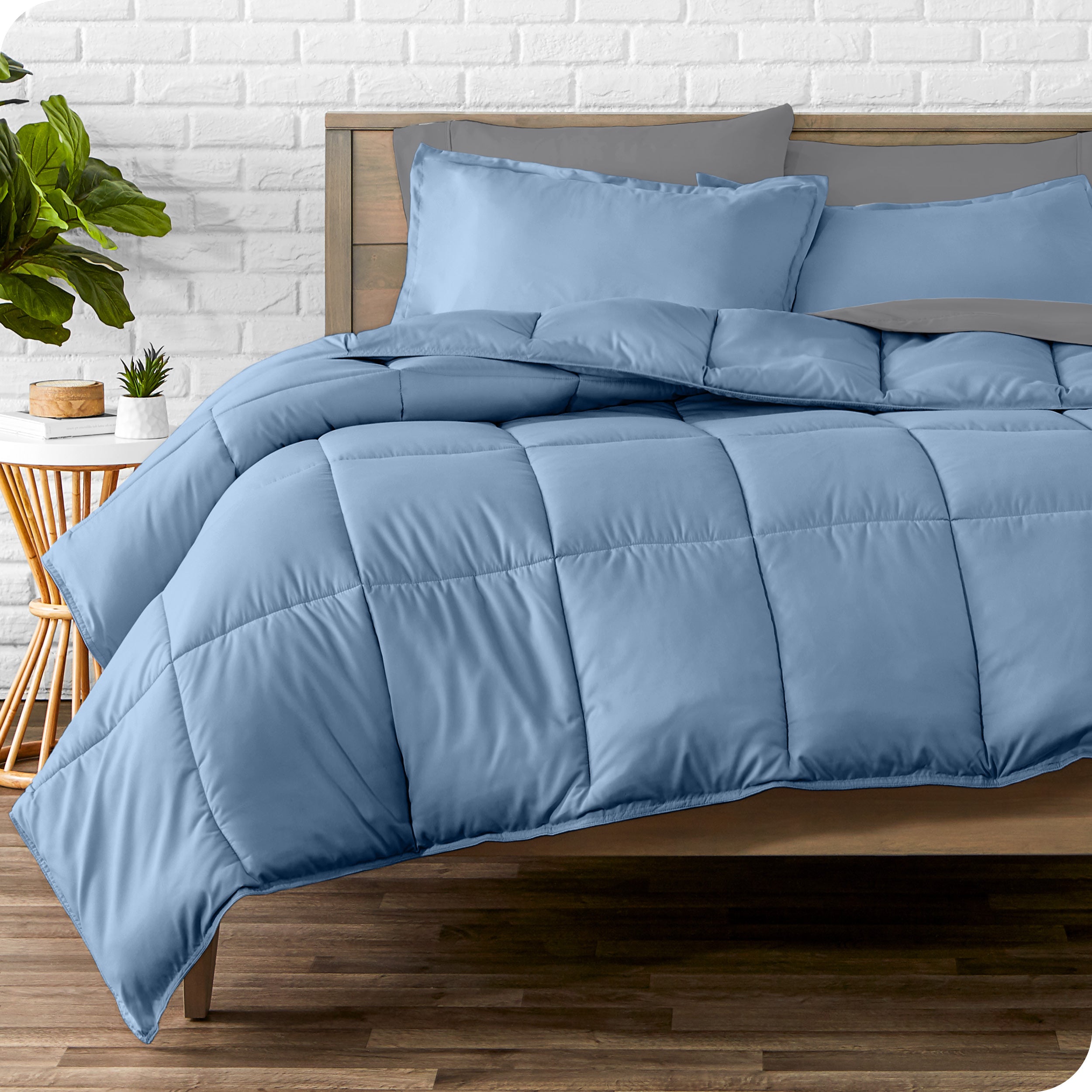 A wooden bed frame with sheets, pillow shams and a comforter on the bed