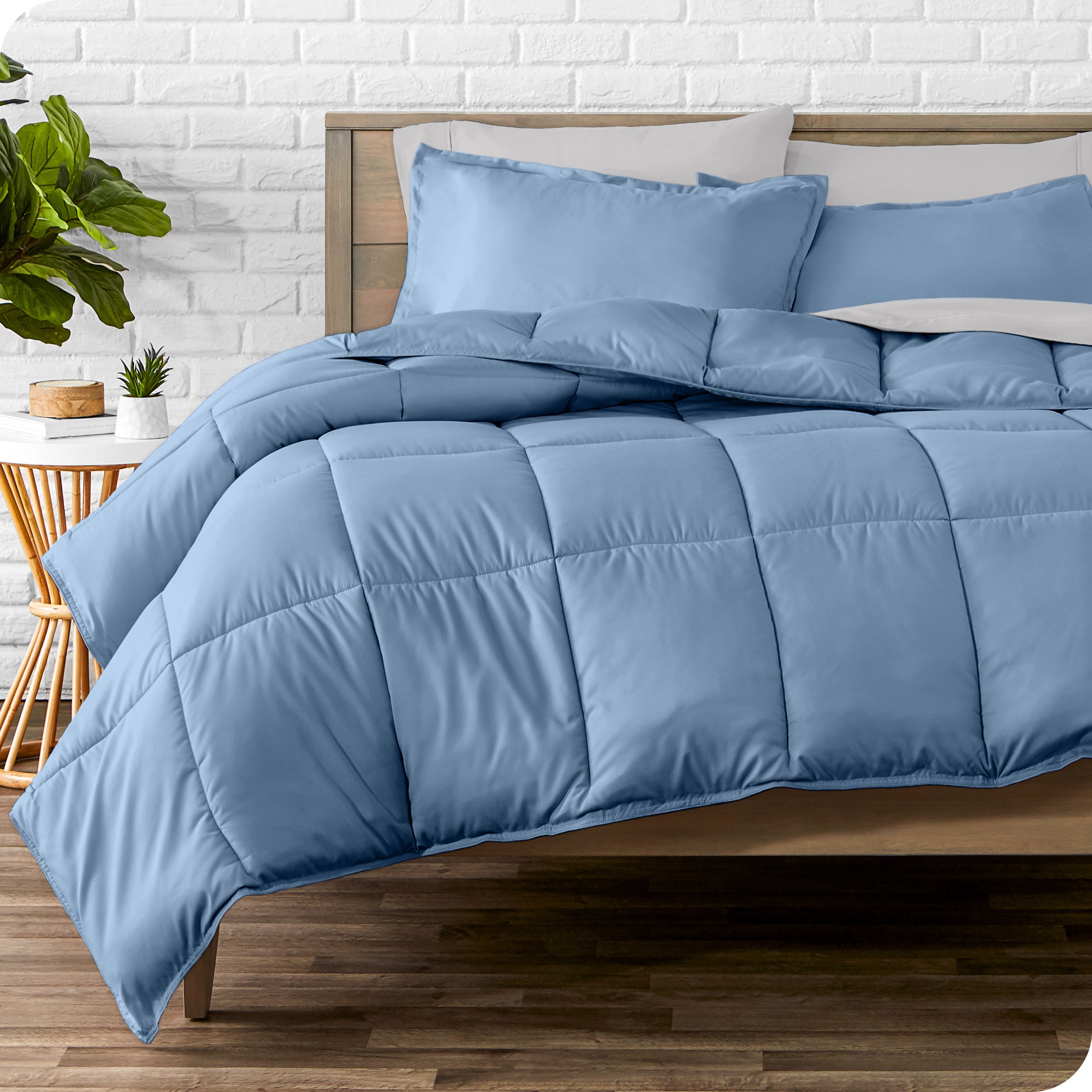 A wooden bed frame with sheets, pillow shams and a comforter on the bed