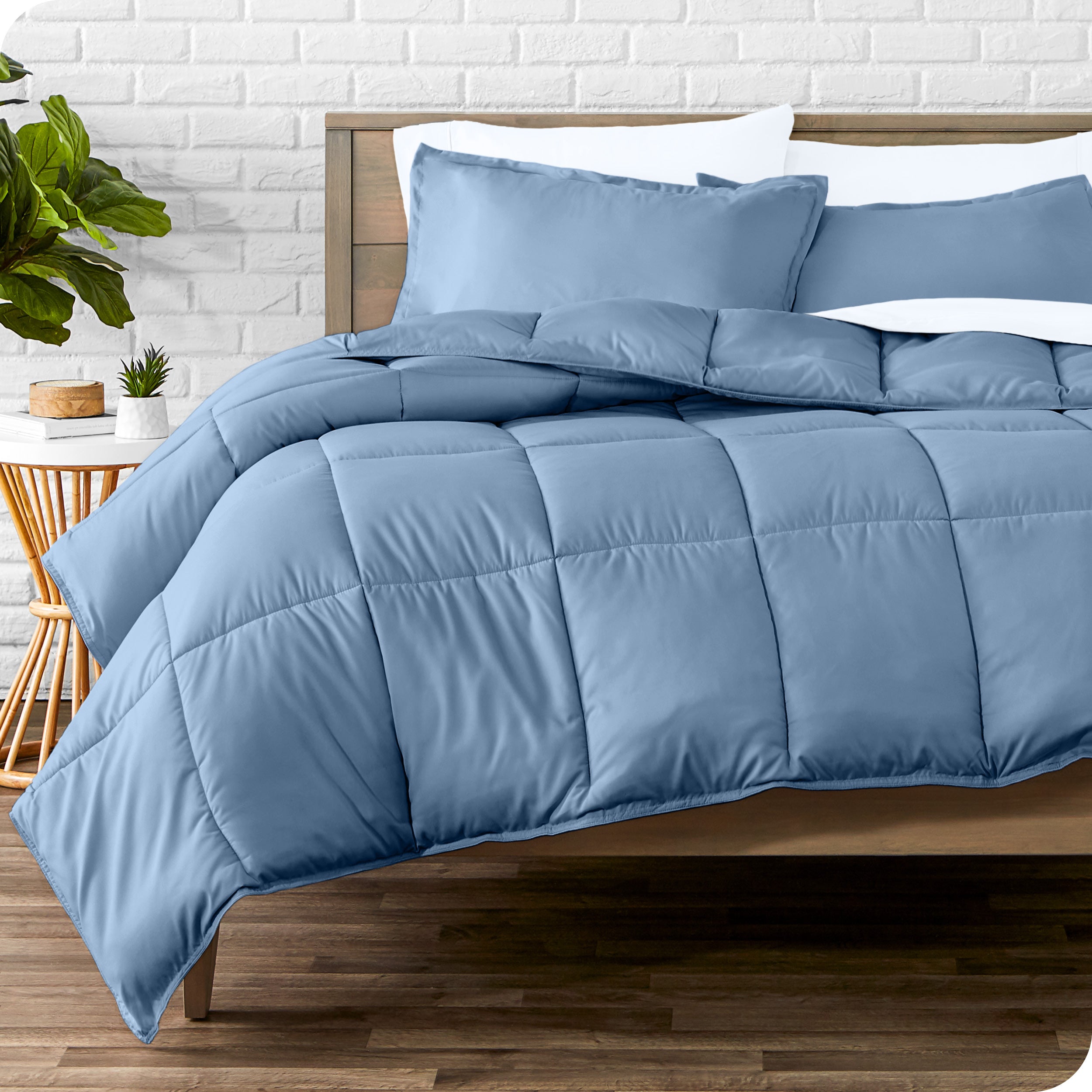 A wooden bed frame with sheets, pillow shams and a comforter on the bed