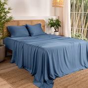Bamboo sheets on a bed in a bedroom with plants and a window.