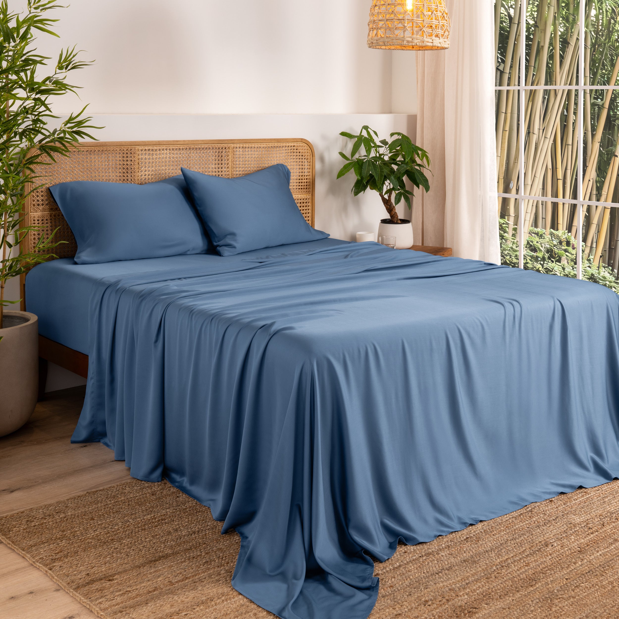 Bamboo sheets on a bed in a bedroom with plants and a window.