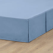 A box spring with a bed skirt on it