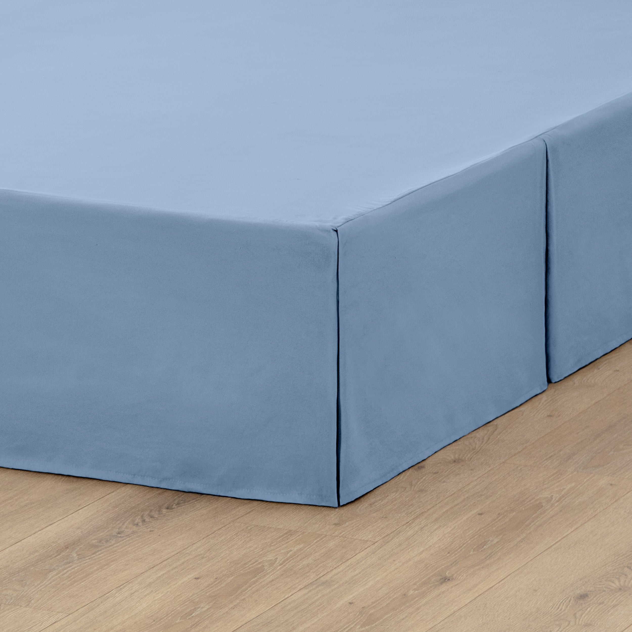 A box spring with a bed skirt on it