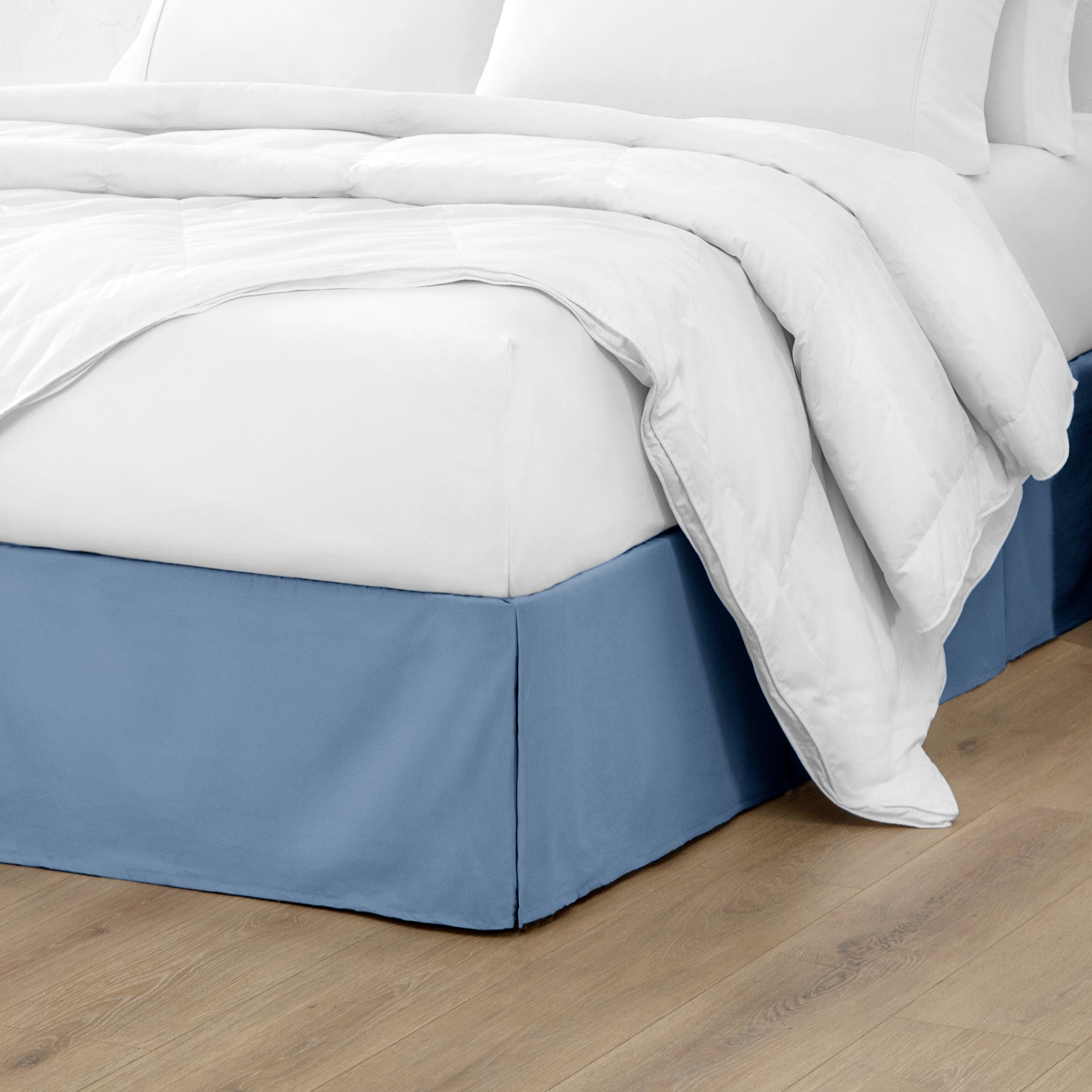 The corner of a bed with a bed skirt and comforter on it
